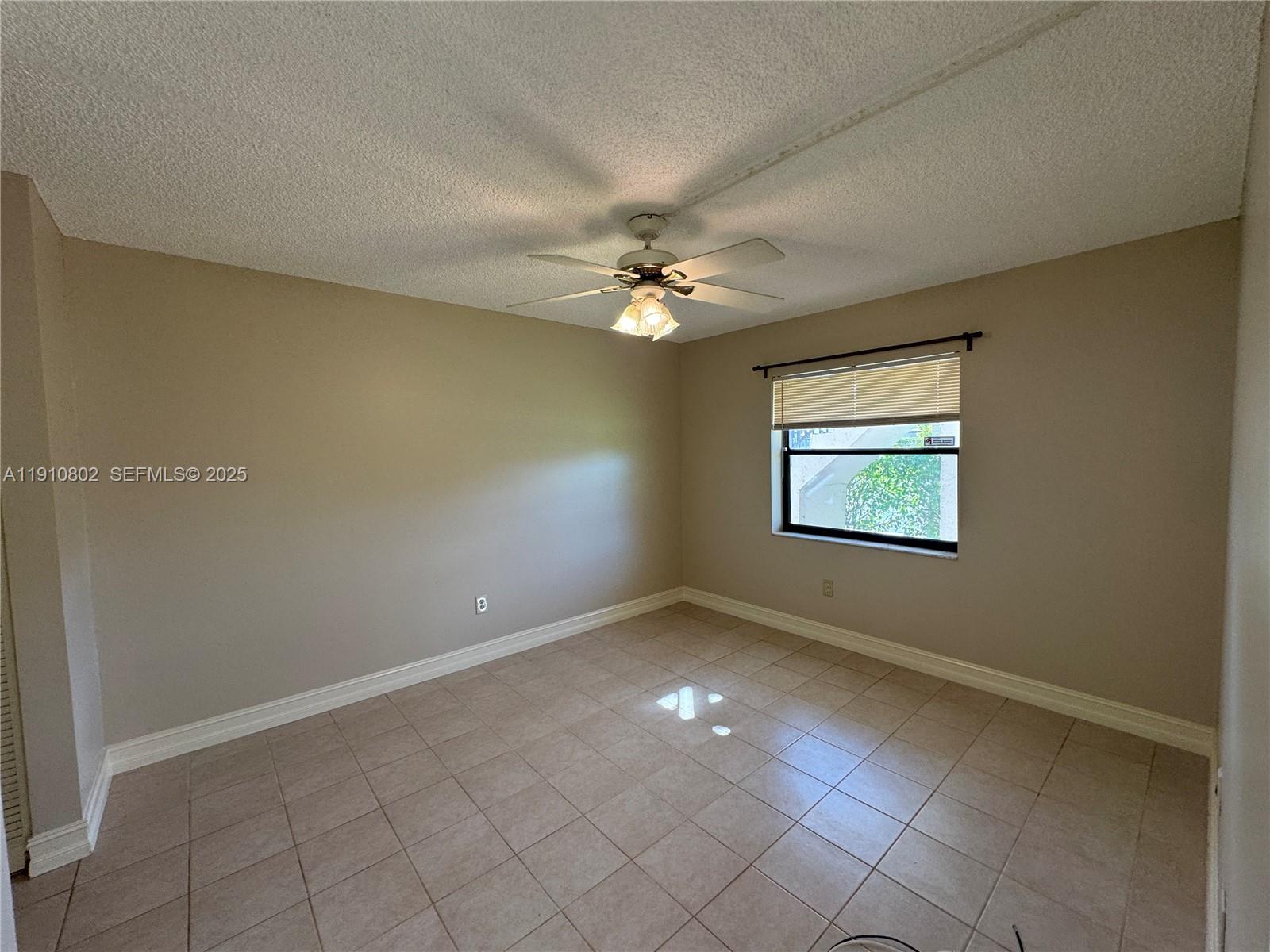 6031 Shaker Wood Circle, Unit 101 Tamarac, FL 33319 - Photo 19 of 28 an empty room with windows and fan