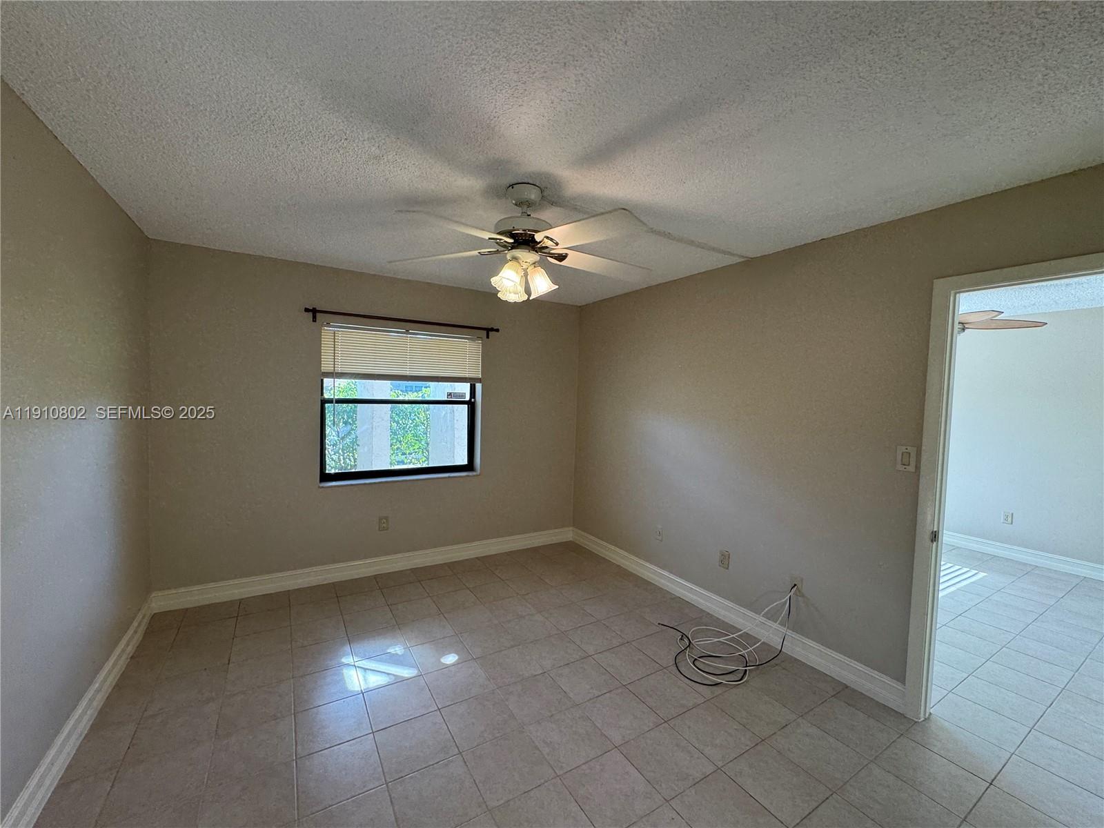 6031 Shaker Wood Circle, Unit 101 Tamarac, FL 33319 - Photo 20 of 28 an empty room with a ceiling fan and window