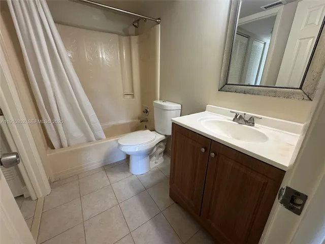 a bathroom with a sink a toilet a mirror and shower curtain