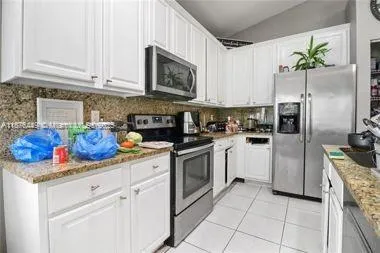 a kitchen with stainless steel appliances granite countertop white cabinets a refrigerator a stove a oven and white cabinets