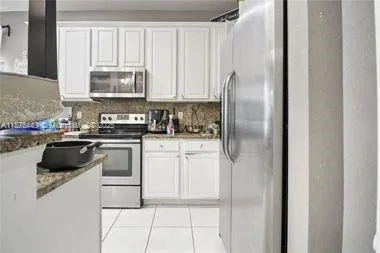a kitchen with white cabinets and appliances