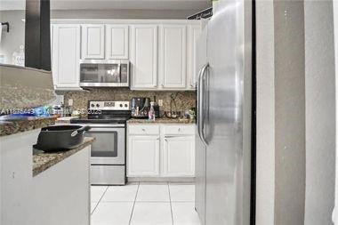 8525 Pine Cay West Palm Beach, FL 33411 - Photo 18 of 40 a kitchen with white cabinets and appliances
