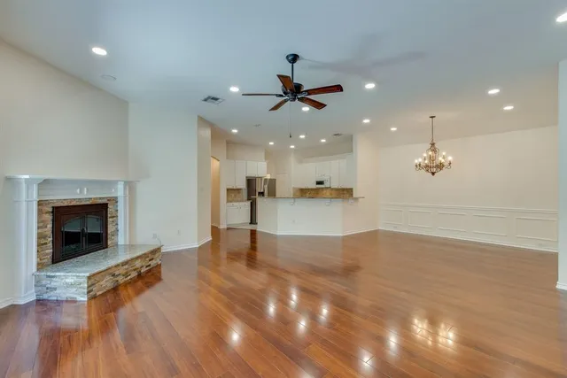 a view of an empty room with kitchen and fireplace