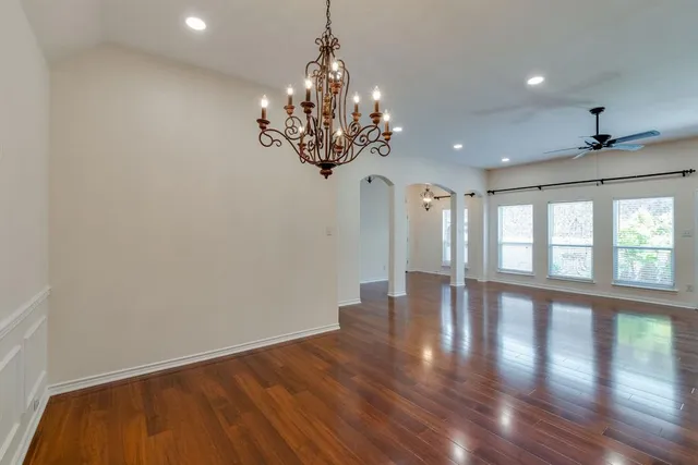 a view of a room with wooden floor chandelier and windows