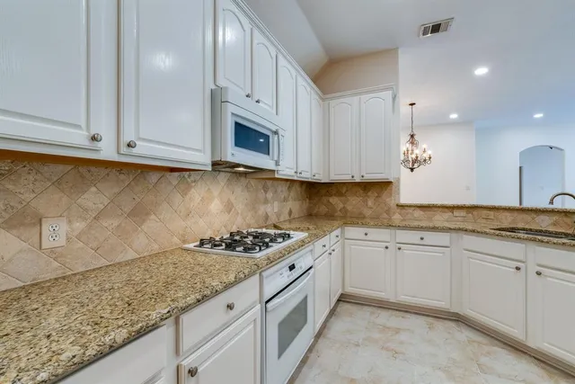 a kitchen with granite countertop white cabinets and sink