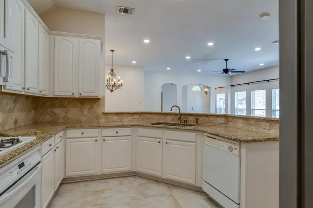 a kitchen with white cabinets sink and stove