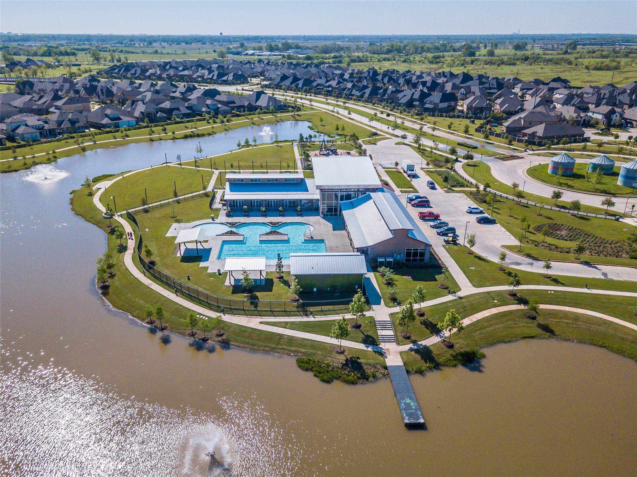 3438 Rich Radish Road Richmond, TX 77406 - Photo 22 of 25 Overlooking one of the community’s central gathering areas, this amenity complex offers open-air spaces designed for recreation, relaxation, and neighborhood events. The combination of waterfront views, landscaped common areas, and family-friendly outdoor features reflects the connected lifestyle Harvest Green is known for.