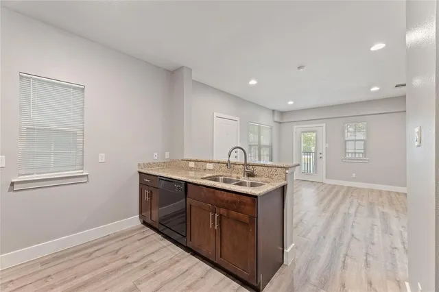a view of an empty room with kitchen and window