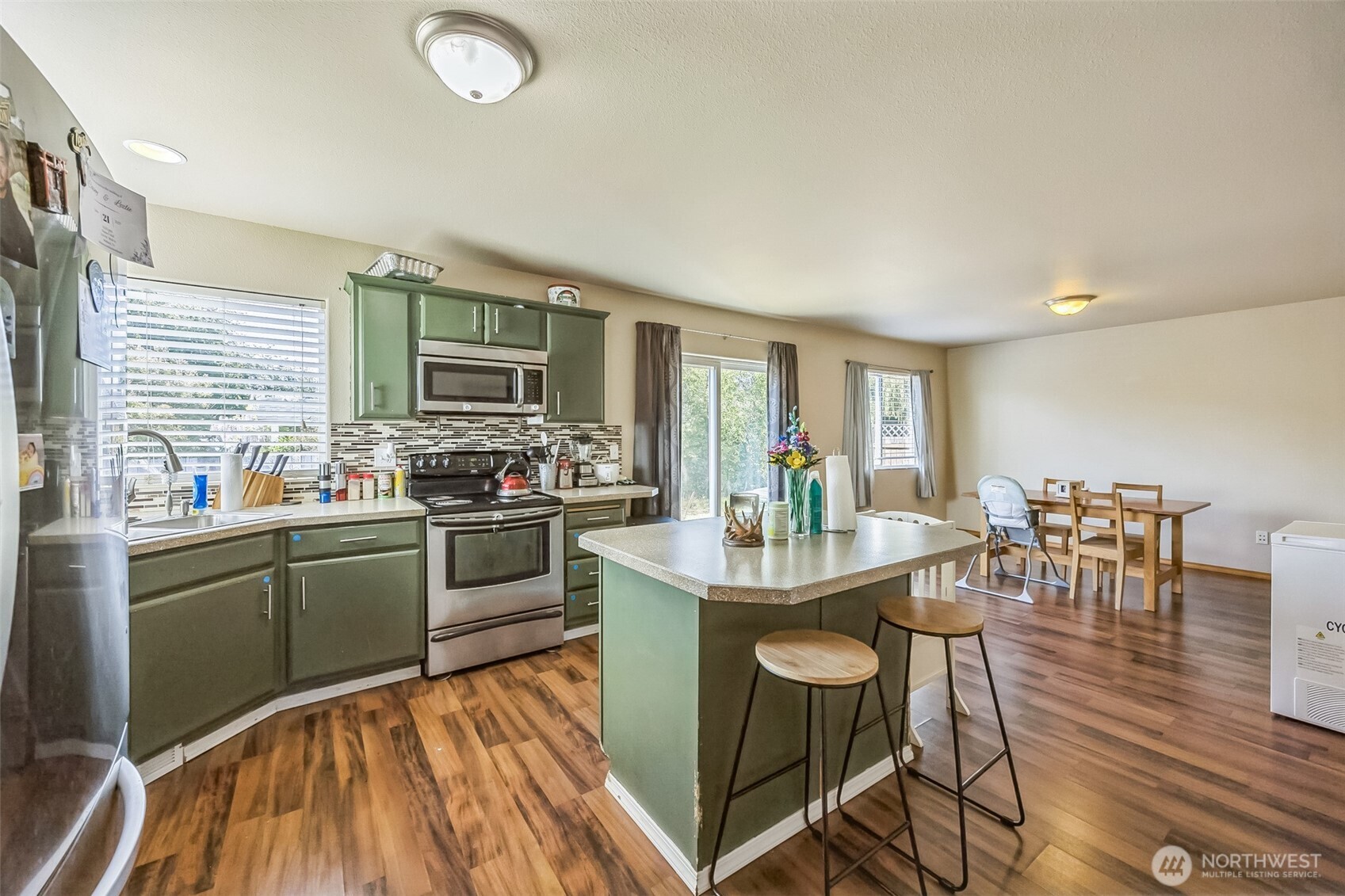 201 3rd Street Northeast Yelm, WA 98597 - Photo 12 of 30 a kitchen with stainless steel appliances granite countertop a stove top oven a sink dishwasher a dining table and chairs with wooden floor