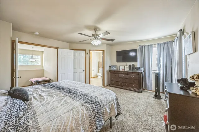 a bedroom with a large bed a flat tv screen and dresser