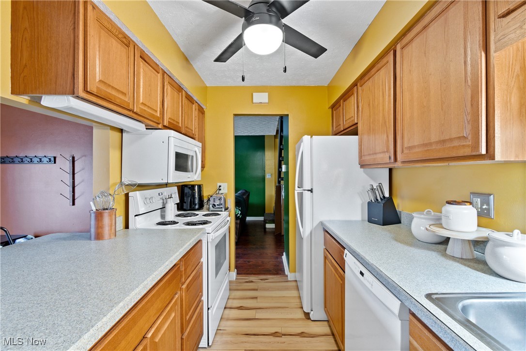 9956 Johnnycake Ridge Road, Unit F4 Painesville, OH 44077 - Photo 11 of 25 Kitchen featuring ceiling fan, white appliances, and light wood-type flooring