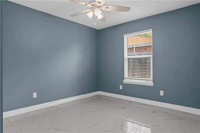 an empty room with a window and a fan