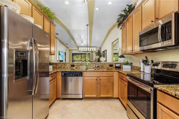 a kitchen with stainless steel appliances granite countertop a stove a sink and a microwave