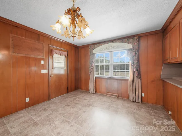 an empty room with chandelier fan and windows