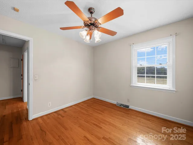 an empty room with wooden floor closet and windows