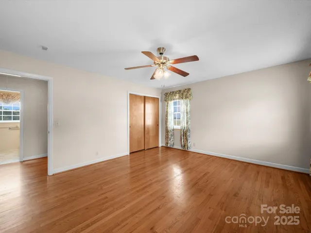 a view of an empty room with window and wooden floor