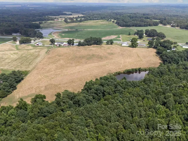 an aerial view of a houses with outdoor space and trees all around