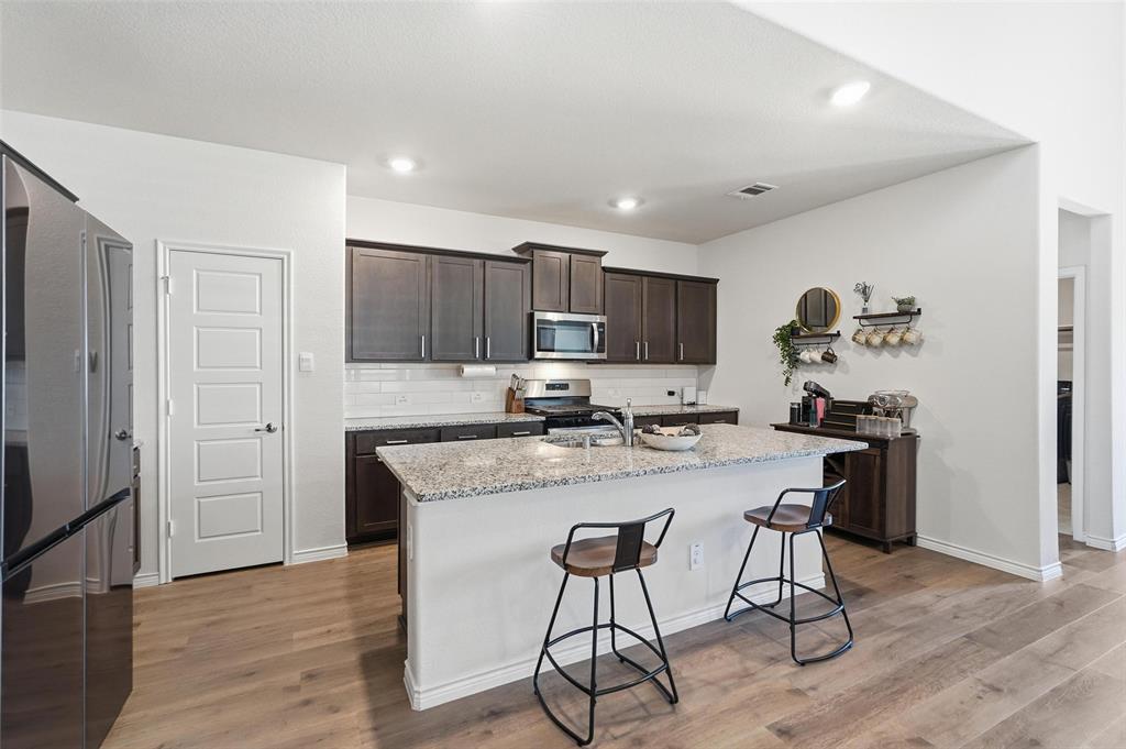 103 Lantern Road Caddo Mills, TX 75135 - Photo 10 of 33 a kitchen with a table chairs refrigerator and wooden cabinets