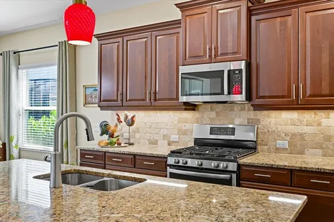 a kitchen with stainless steel appliances granite countertop a stove a sink and a microwave