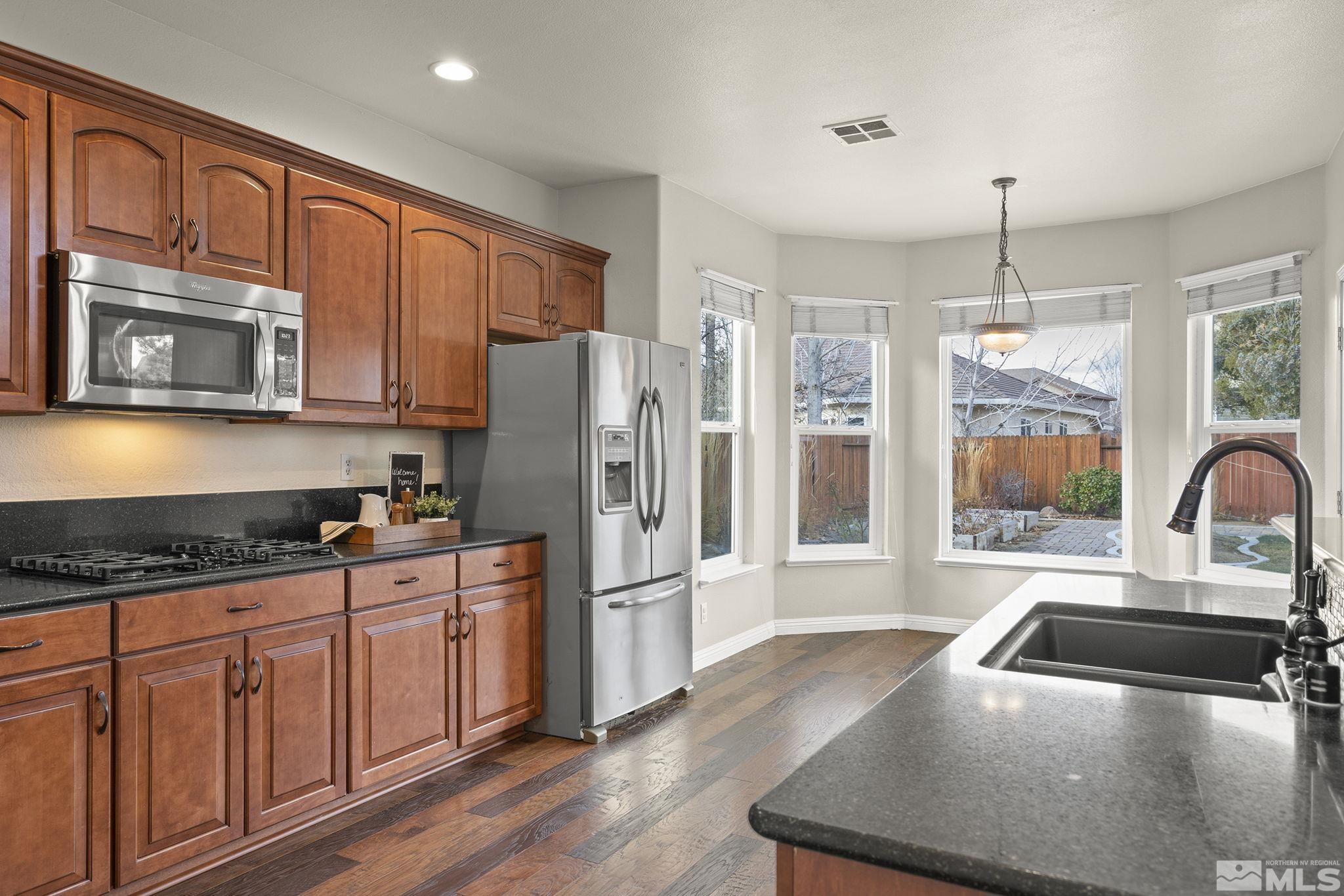 9965 Bandana Way Reno, NV 89521 - Photo 7 of 40 a kitchen with stainless steel appliances granite countertop a refrigerator a stove a sink dishwasher and wooden cabinets with wooden floor