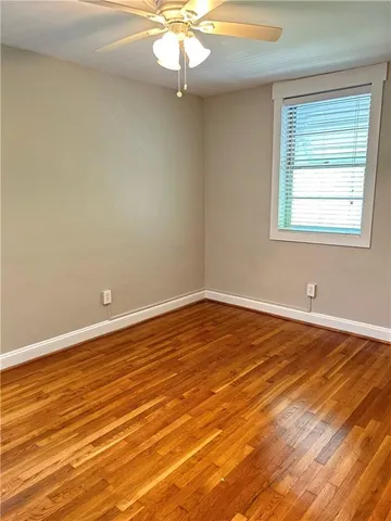 an empty room with wooden floor fan and window
