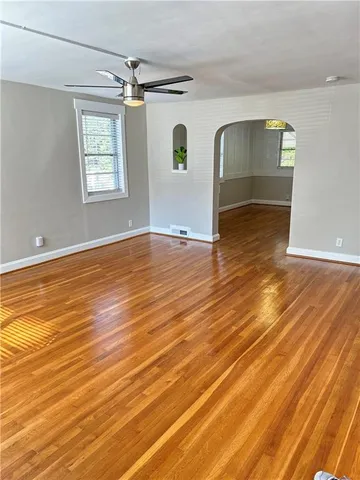 a view of empty room with wooden floor and fan