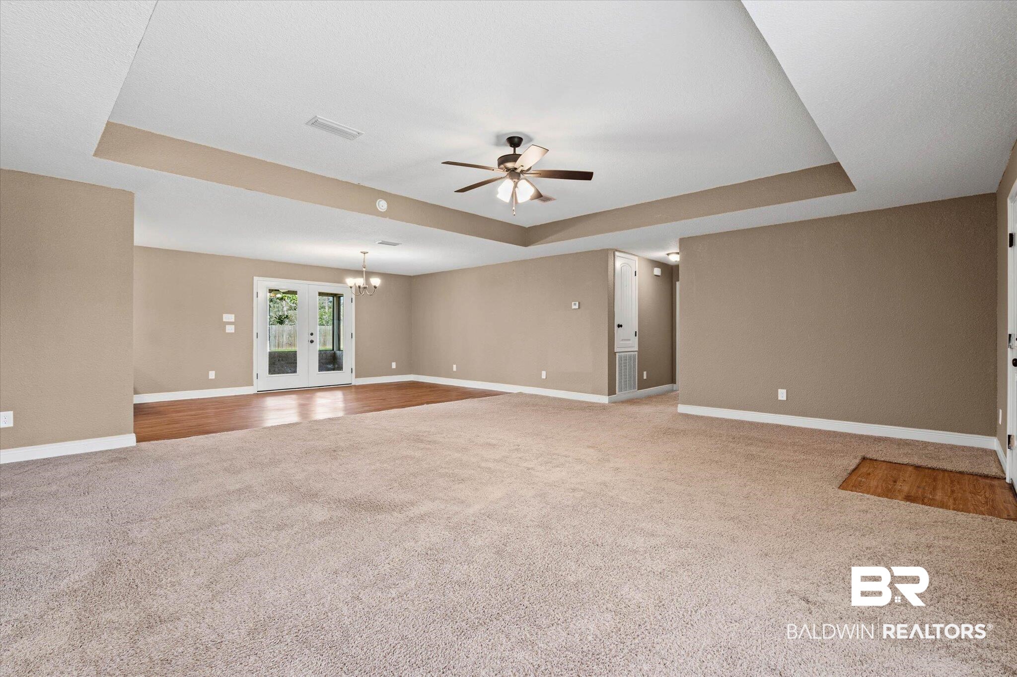 101 Washington Boulevard Foley, AL 36535 - Photo 3 of 32 Unfurnished living room with a raised ceiling, ceiling fan, light carpet, hanging lights, and french doors