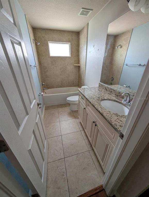 6394 Banyan Boulevard, Unit 204 New Port Richey, FL 34652 - Photo 14 of 25 a spacious bathroom with a granite countertop sink a toilet a mirror and shower