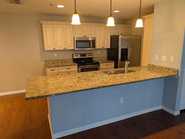 a kitchen with kitchen island granite countertop a sink a counter top space appliances and cabinets