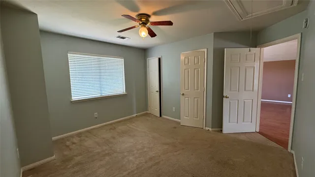 an empty room with windows and fan