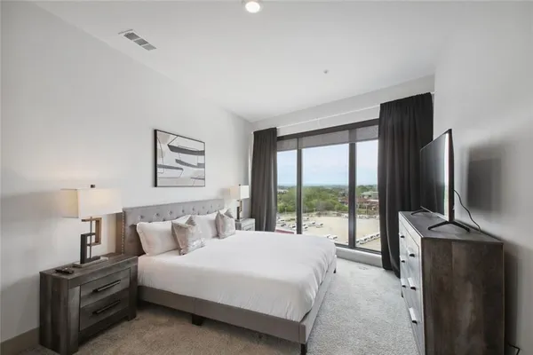 a bedroom with a bed flat screen tv and a large window