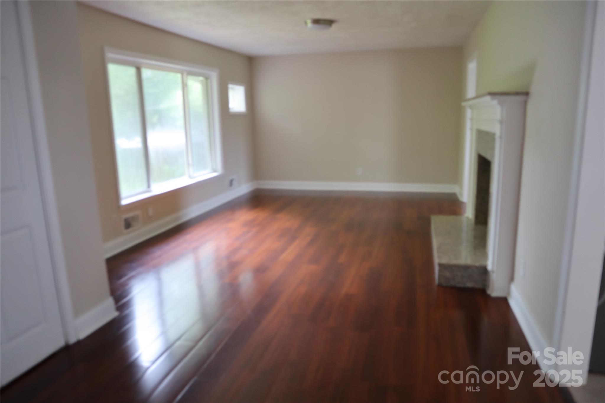 1703 Tyvola Road Charlotte, NC 28210 - Photo 4 of 17 a view of an empty room with wooden floor and a window