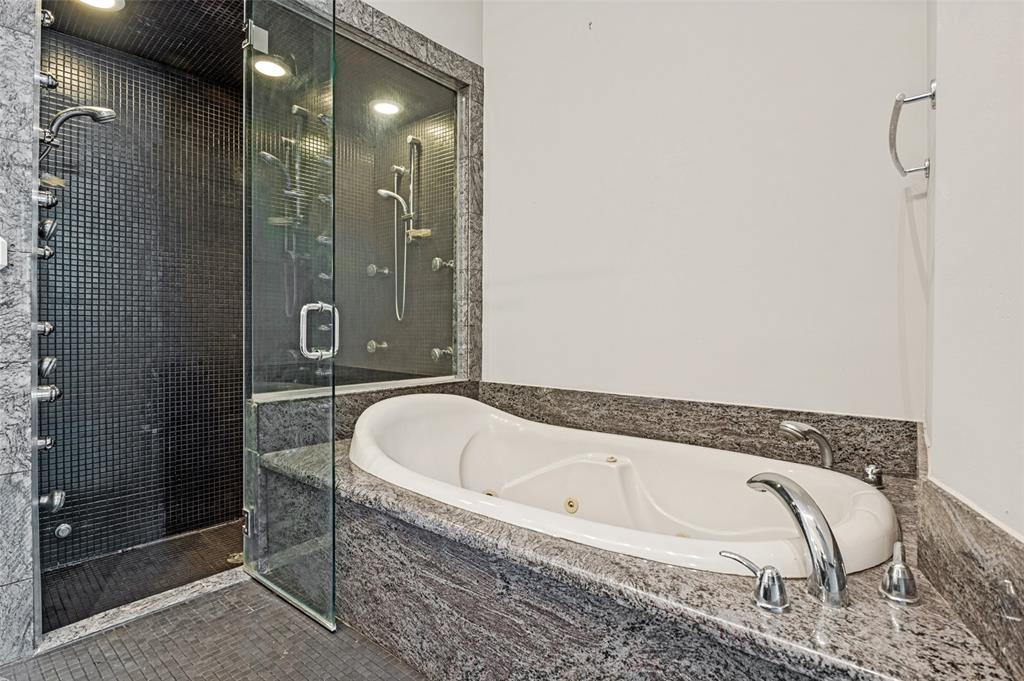 2220 Canton Street, Unit 101 Dallas, TX 75201 - Photo 8 of 20 Spa-inspired bath featuring a jetted soaking tub with polished chrome fixtures, a multi-head shower with glass enclosure, dark mosaic tile walls and floor, and granite surfacing