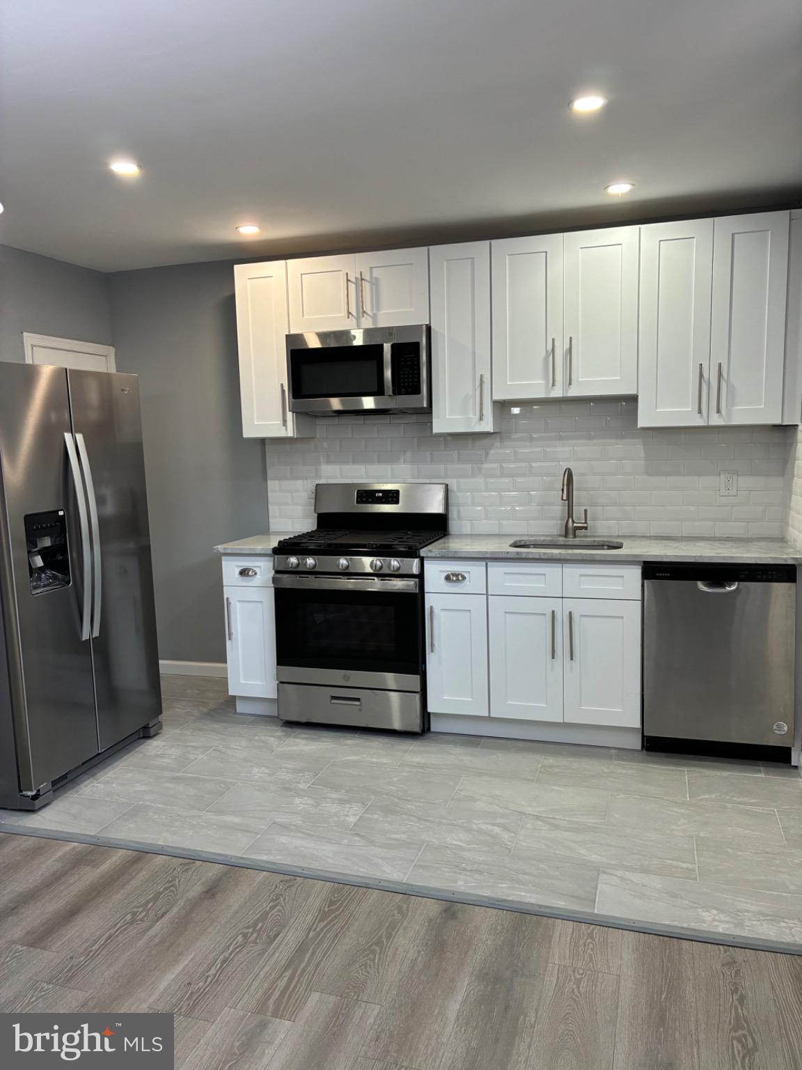 6733 Linmore Avenue Philadelphia, PA 19142 - Photo 36 of 55 a kitchen with stainless steel appliances granite countertop a stove a sink a refrigerator a microwave and cabinets