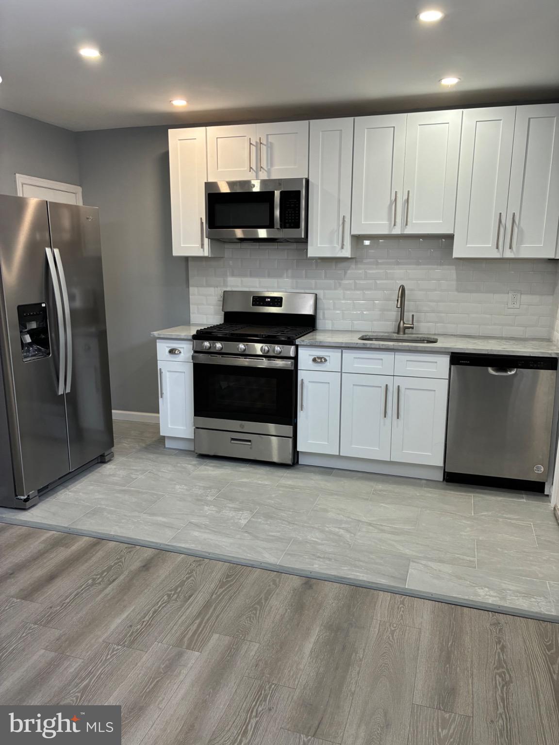 6733 Linmore Avenue Philadelphia, PA 19142 - Photo 37 of 55 a kitchen with stainless steel appliances granite countertop a stove a sink and a microwave