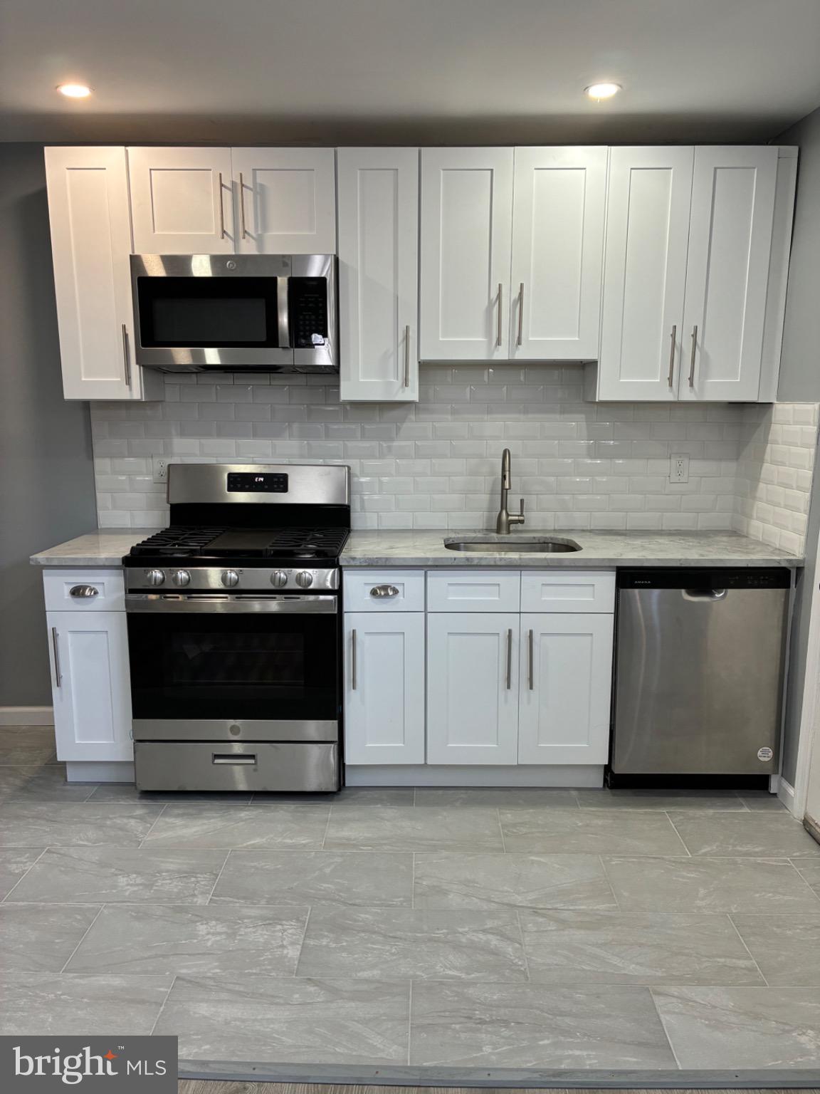 6733 Linmore Avenue Philadelphia, PA 19142 - Photo 39 of 55 a kitchen with stainless steel appliances granite countertop a stove a microwave and oven