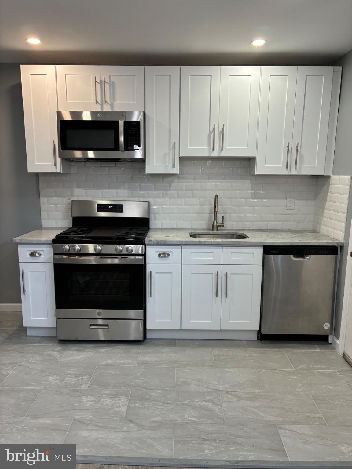 6733 Linmore Avenue Philadelphia, PA 19142 - Photo 40 of 55 a kitchen with stainless steel appliances granite countertop a stove a microwave and oven