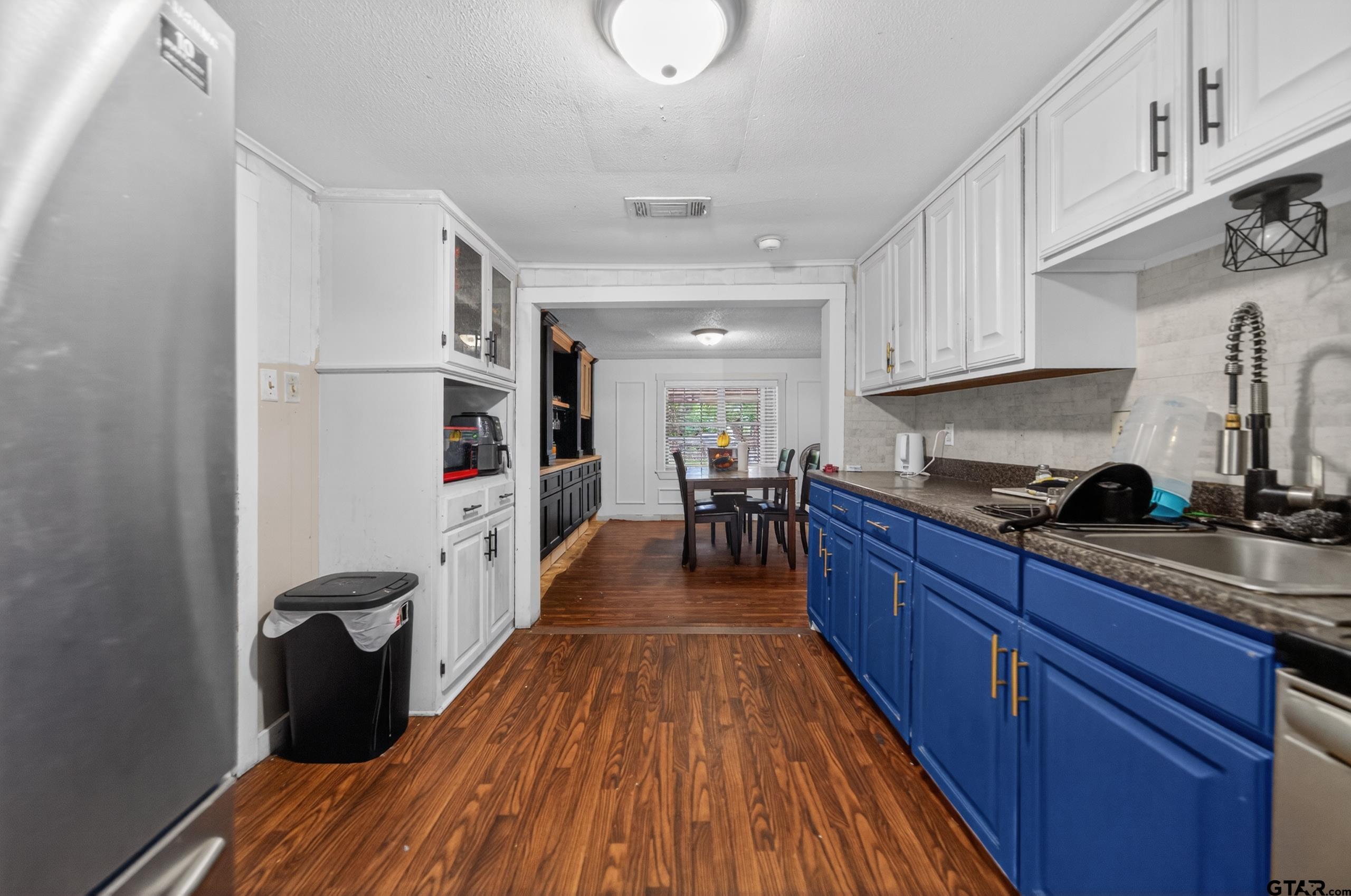 319 McArthur Street Athens, TX 75751 - Photo 10 of 33 a kitchen with stainless steel appliances granite countertop wooden floors a stove and white cabinets
