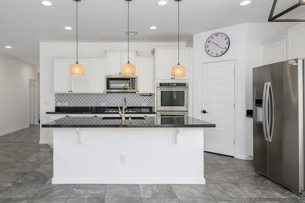 a kitchen with stainless steel appliances granite countertop a sink a stove and a refrigerator