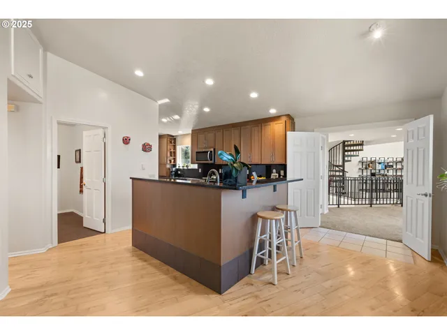 a kitchen with stainless steel appliances kitchen island granite countertop a refrigerator a stove and a sink