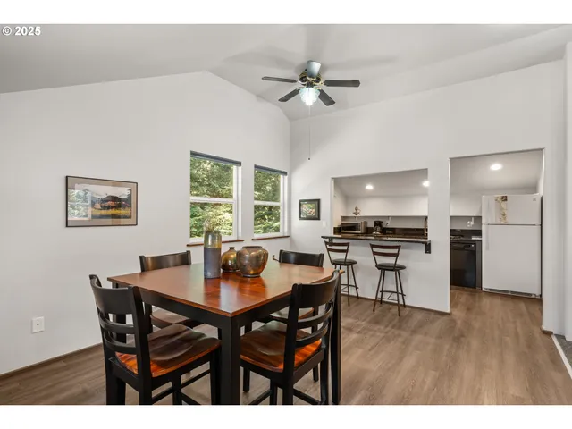 a kitchen with stainless steel appliances kitchen island granite countertop a dining table chairs and a refrigerator