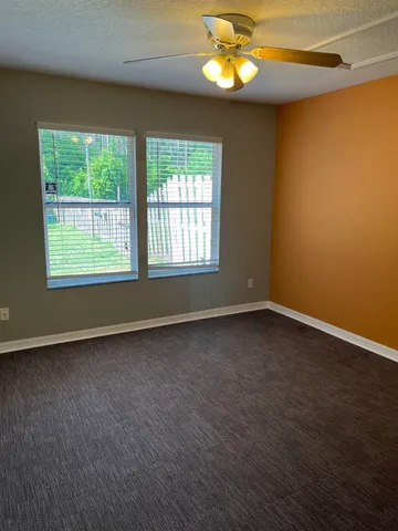 an empty room with a window and ceiling fan