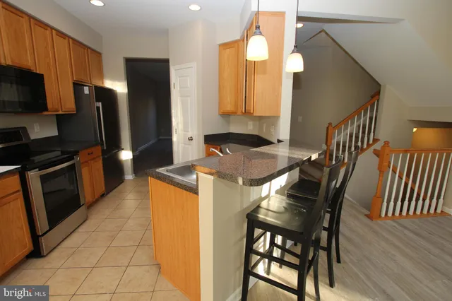 a kitchen with stainless steel appliances kitchen island granite countertop a stove a sink a microwave and a refrigerator