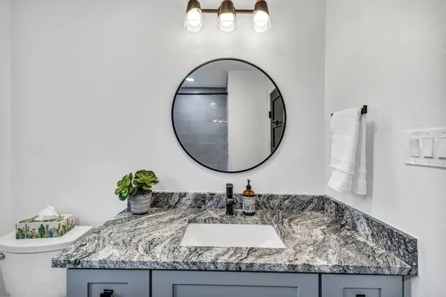a bathroom with a granite countertop sink and a mirror