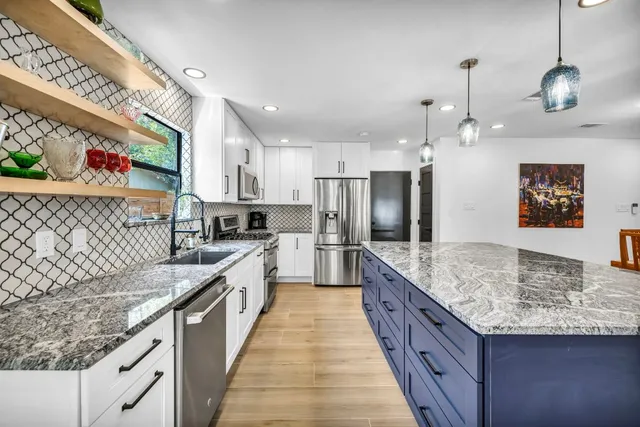 a large kitchen with stainless steel appliances granite countertop a sink stove and refrigerator