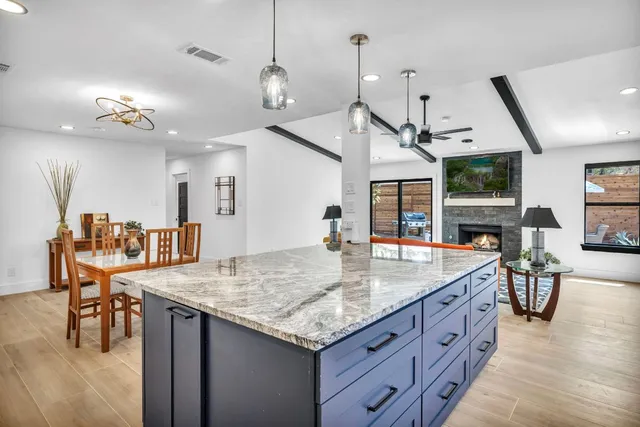 a kitchen with granite countertop a stove a sink a dining table and chairs
