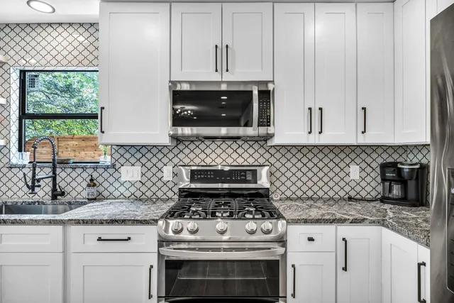 a kitchen with granite countertop a stove sink and cabinets