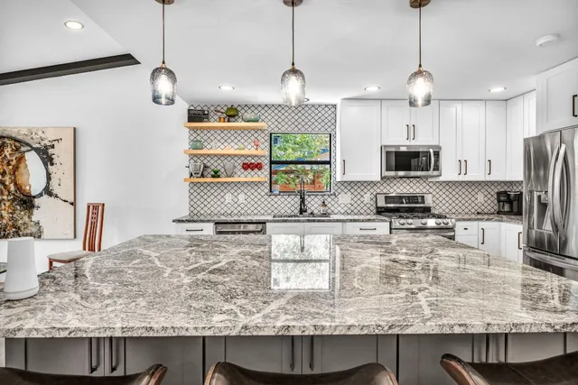 a kitchen with kitchen island granite countertop a sink and microwave