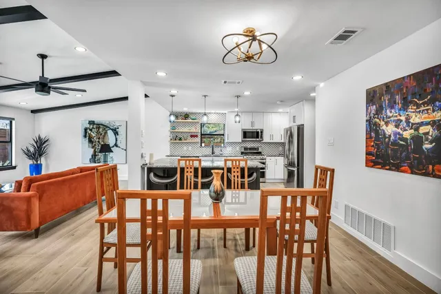 a view of a dining room with furniture a kitchen and chandelier