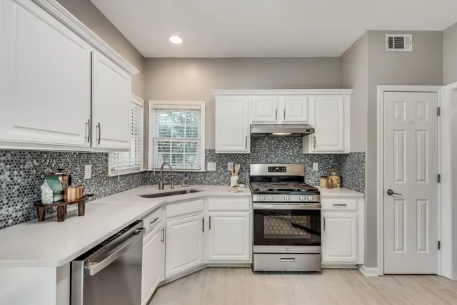 a kitchen with granite countertop a stove sink and cabinets